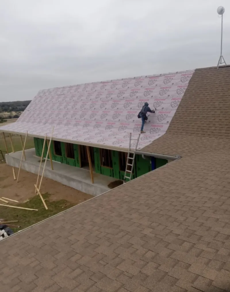 Worker preparing underlayment for a metal roof installation in South Lebanon